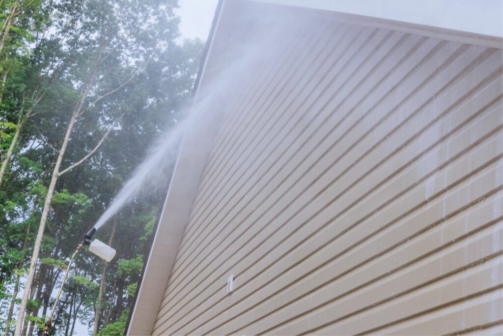 TM Exterior Solutions LLC crew pressure washing stained home siding and trim