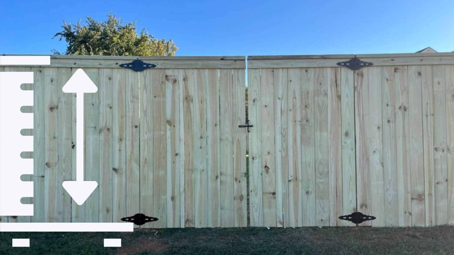 Worker measuring wooden privacy fence with double gate and black strap hinges