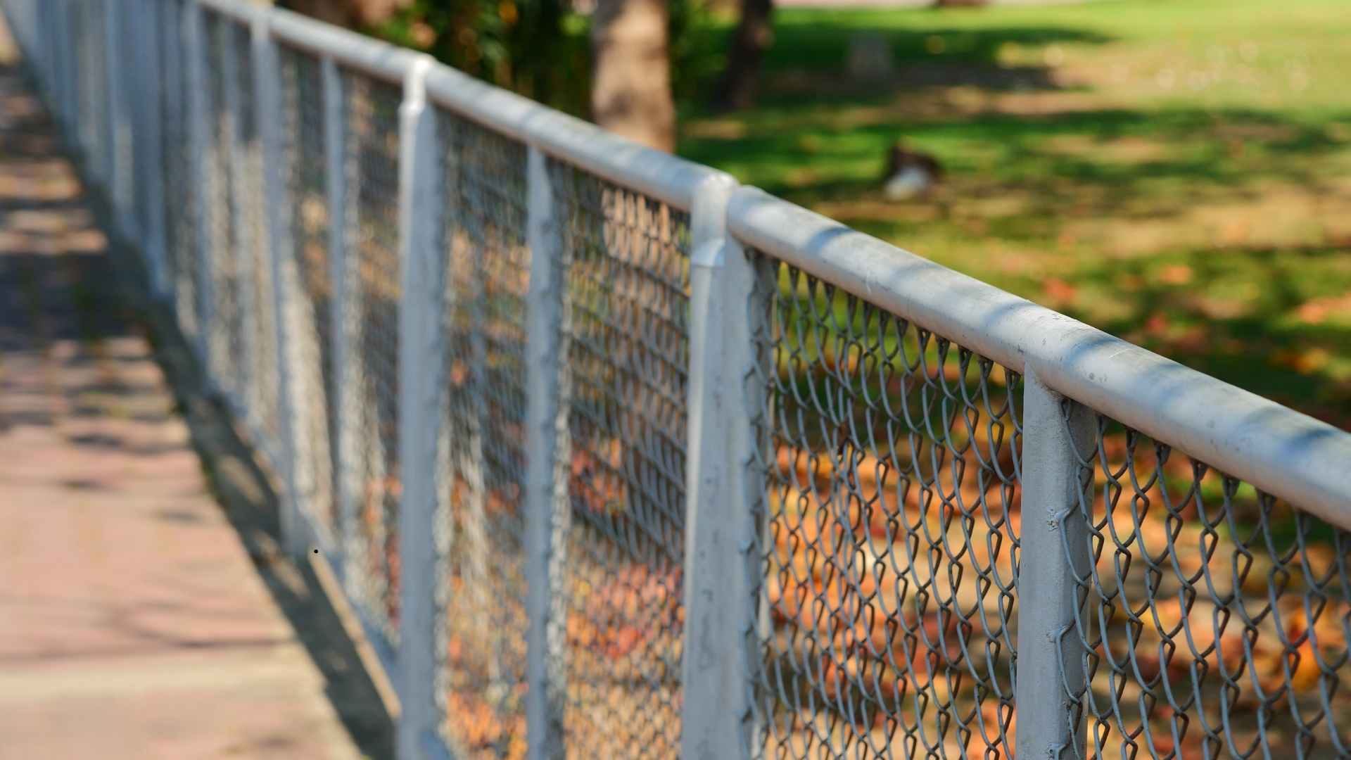 Technician installing new chain link fence along residential yard boundary
