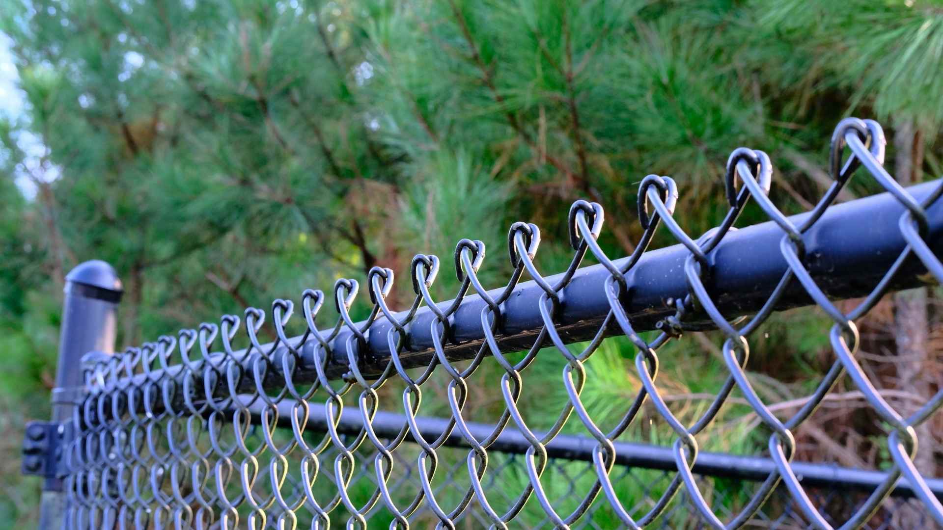 Technician installing chain link fence panels at a residential yard, TM Exterior Solutions LLC